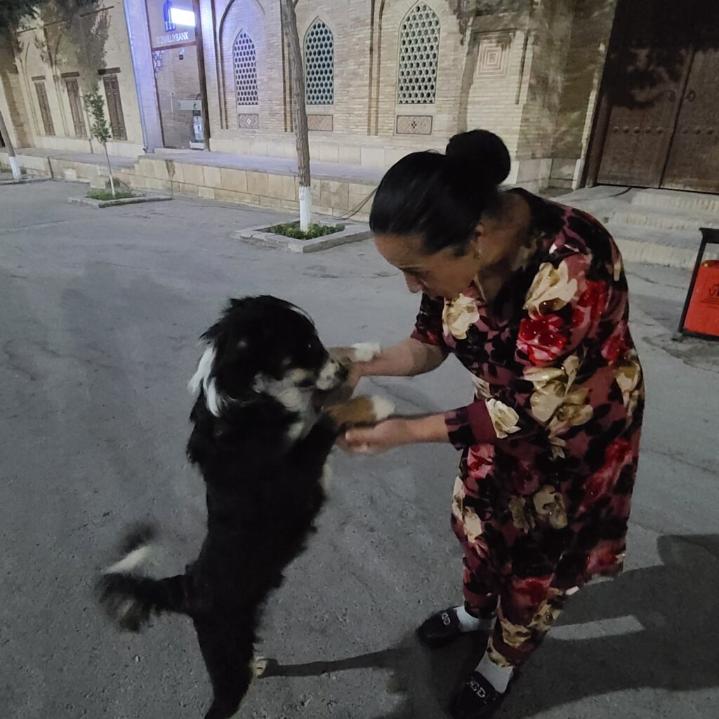 Uzbek lady playing with a dog in Bukhara
